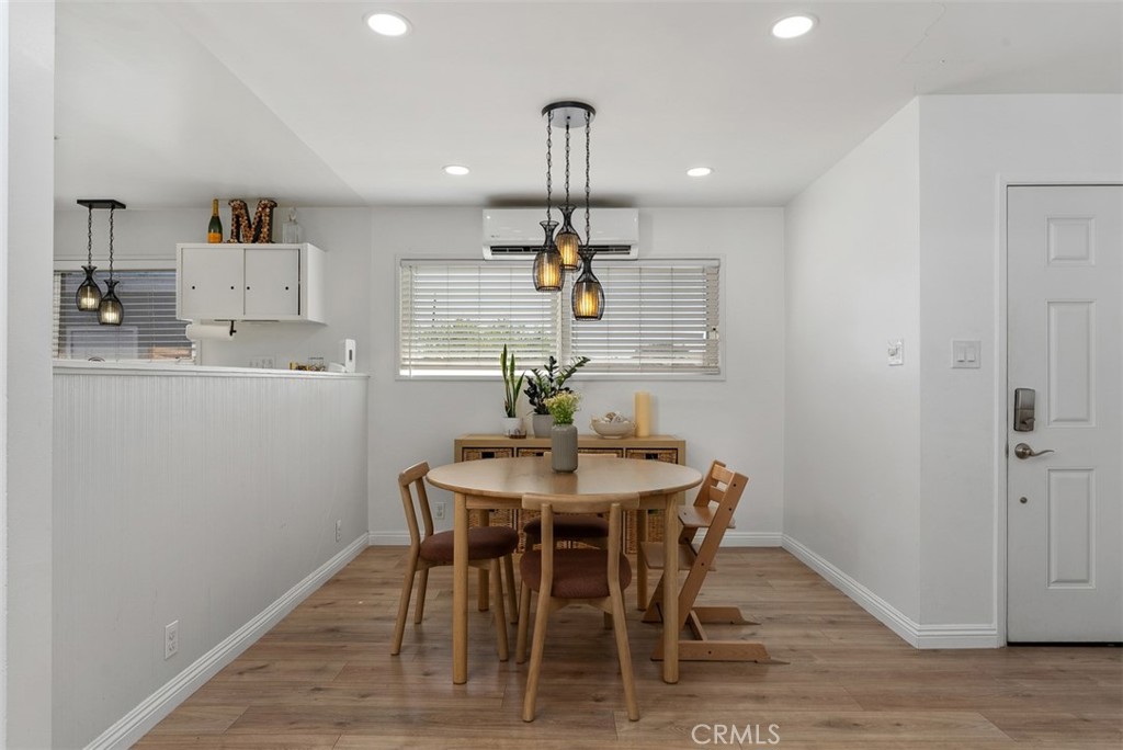 Dining area at 9925 Rutland Avenue with a round wooden table and chairs beneath pendant lights, beside an open kitchen.