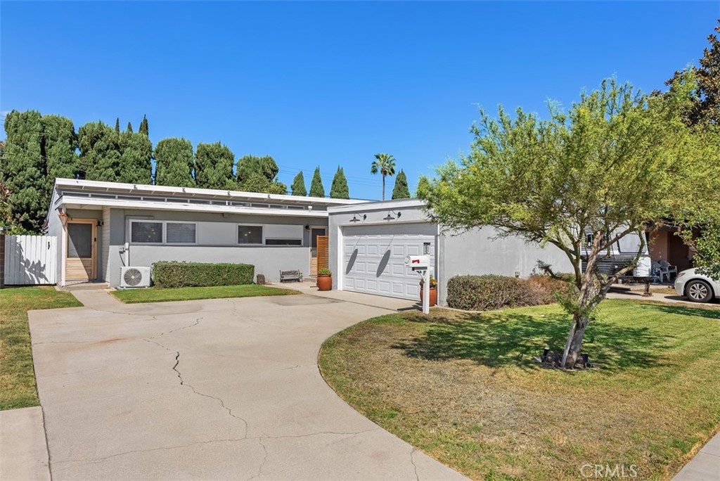 Single-story mid-century home at 9925 Rutland Avenue with a wide concrete driveway, attached garage, front lawn, and mature trees.