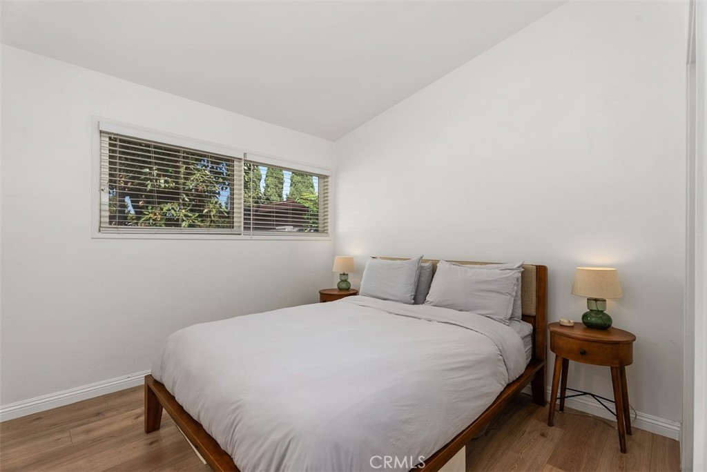 Bedroom at 9925 Rutland Avenue with a wooden bed, gray bedding, matching bedside tables, and a wide window.