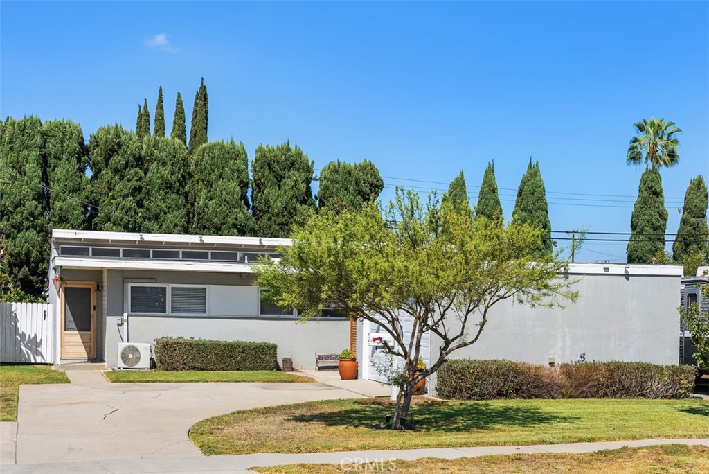 Street view of the single-story modern home at 9925 Rutland Avenue, with a wide driveway, front lawn, and mature trees.