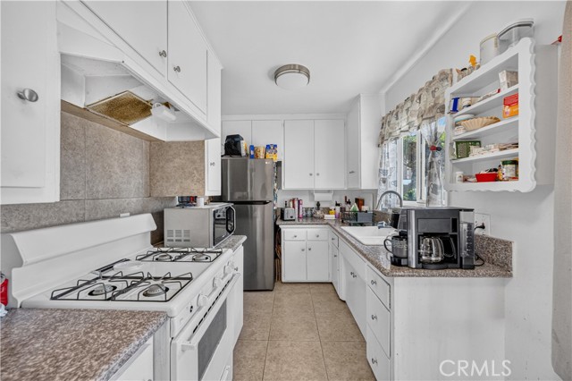 A standard residential kitchen with white cabinetry, tile countertops, and stainless steel appliances.