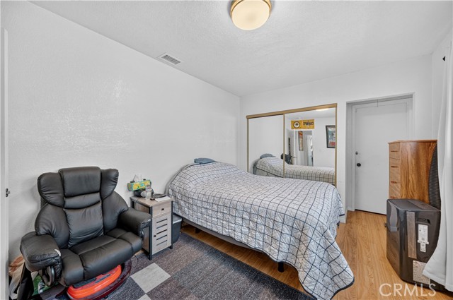 A bedroom with a bed with a grid-pattern quilt, a leather recliner, and mirrored closet doors.