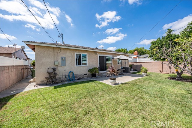 A backyard view of the back of a single-story home with a small patio and a lawn.