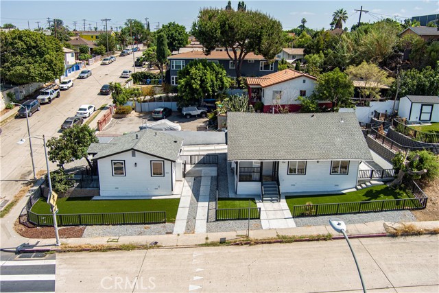 Aerial view of two white cottages with grey roofs and green lawns from the street