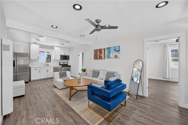 An open floor plan living room with a kitchen in the background, a blue velvet chair, a wooden coffee table, and a gray sofa.