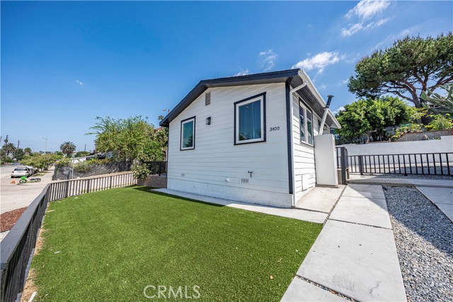 A exterior shot of a house with white siding and artificial grass yard