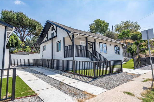 A exterior shot of a modern white bungalow with black trim and a fenced yard under a clear blue sky