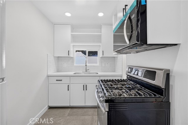 Modern white kitchen with stainless steel gas range and white subway tile backsplash
