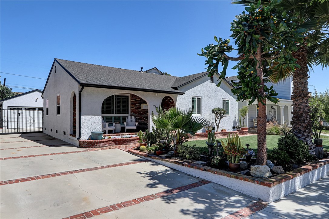 Single-story stucco home at 910 Firmona Avenue, with a brick-trimmed driveway, gated side yard, and landscaped front garden.