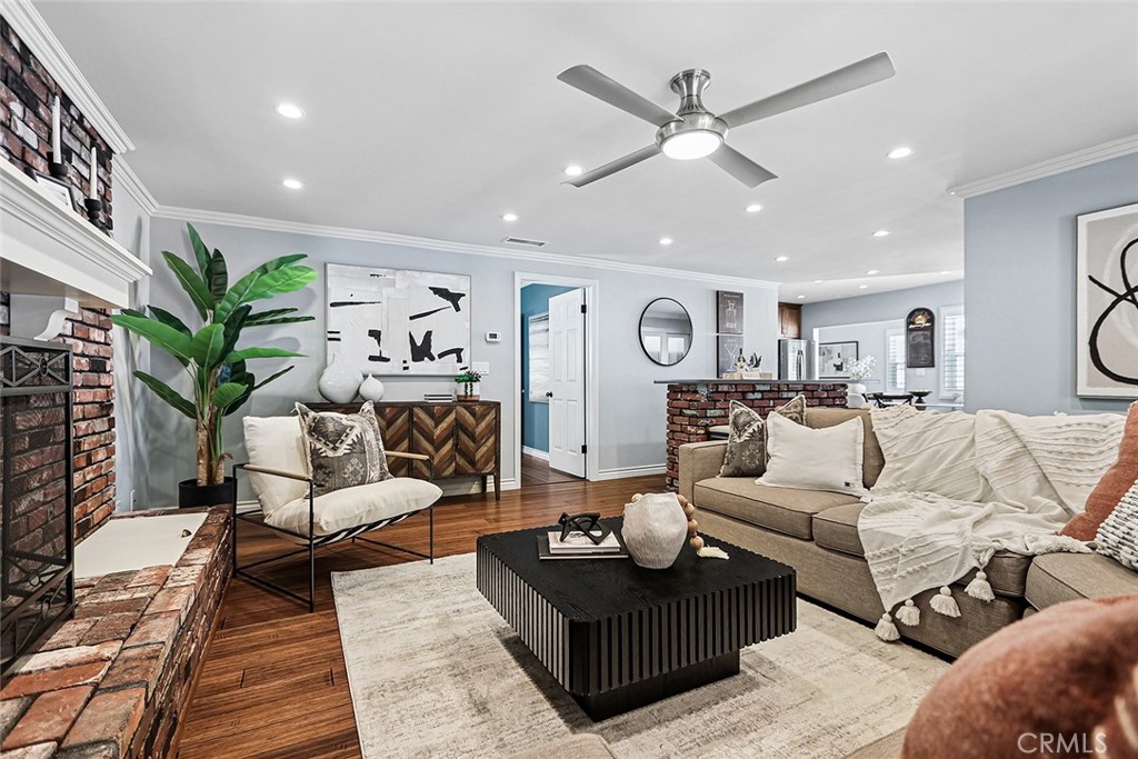 Living room at 910 Firmona Avenue with a brick fireplace, hardwood floors, neutral sofas, a black coffee table, and an open view to the kitchen.