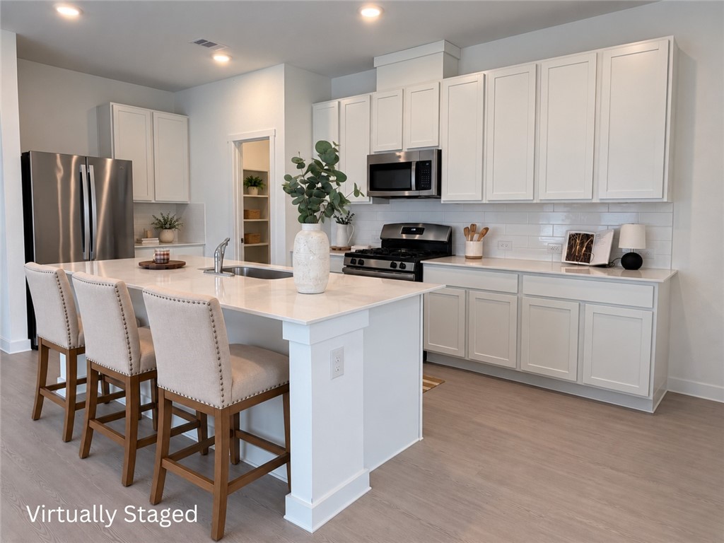 Bright kitchen with white cabinets, stainless steel appliances, and a large island with seating.