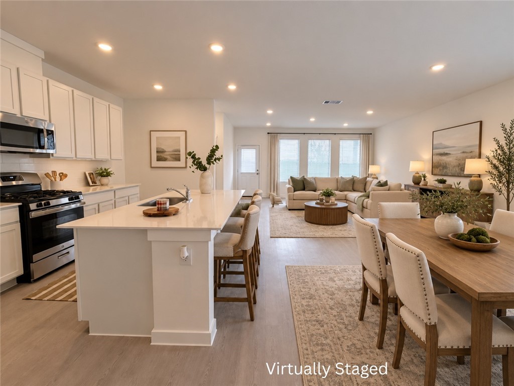 Open-plan kitchen, dining area, and living room with white cabinetry and a large island.