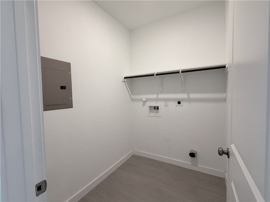 Empty laundry room with a wall shelf and washer and dryer hookups.