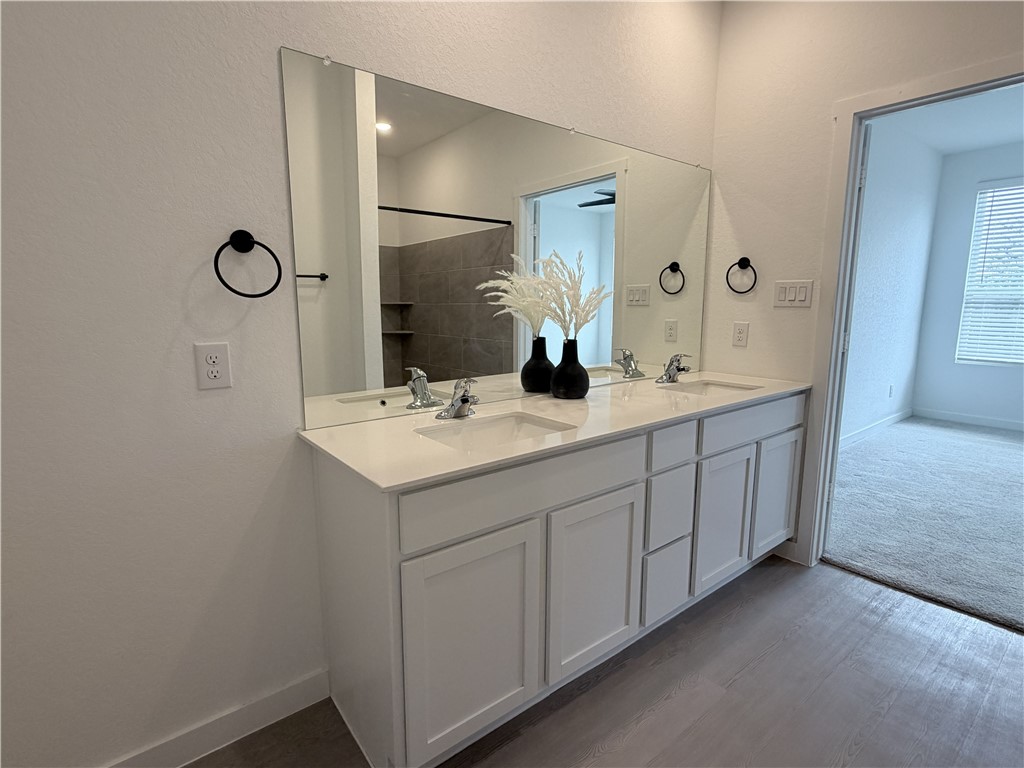 Bathroom vanity with two sinks, white cabinets, and a wide mirror above.