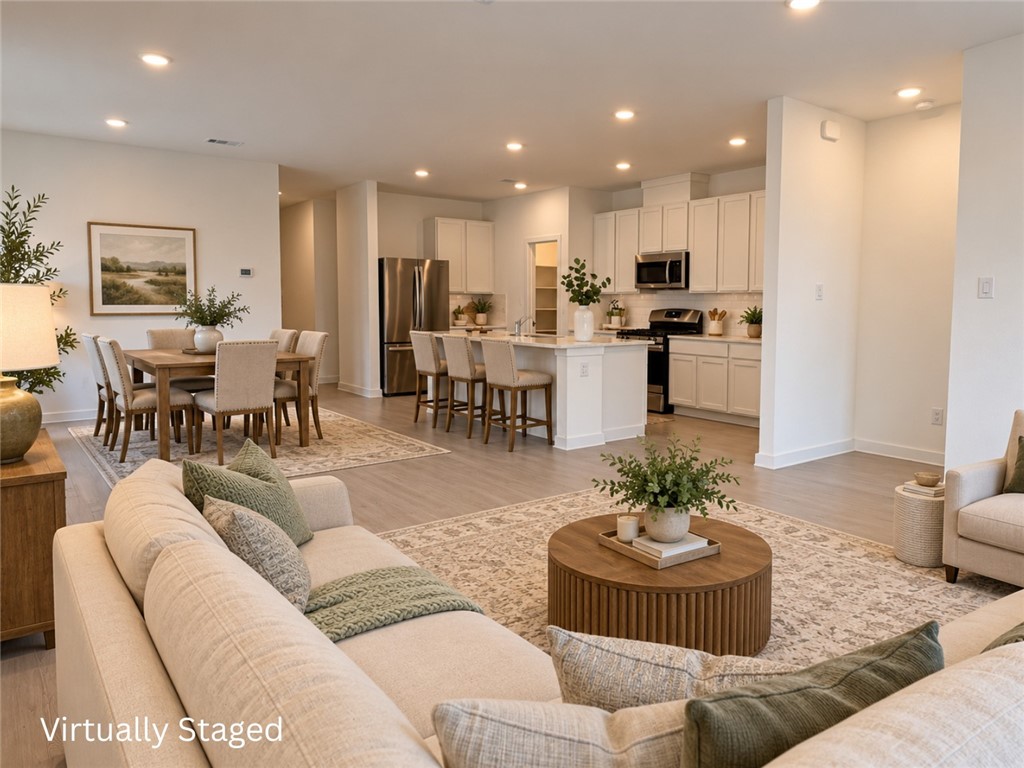 Open-plan living room, dining area, and kitchen with a breakfast island and light cabinetry.