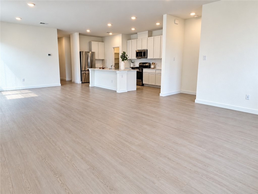 Open living area with light wood flooring and a white kitchen island and cabinets.