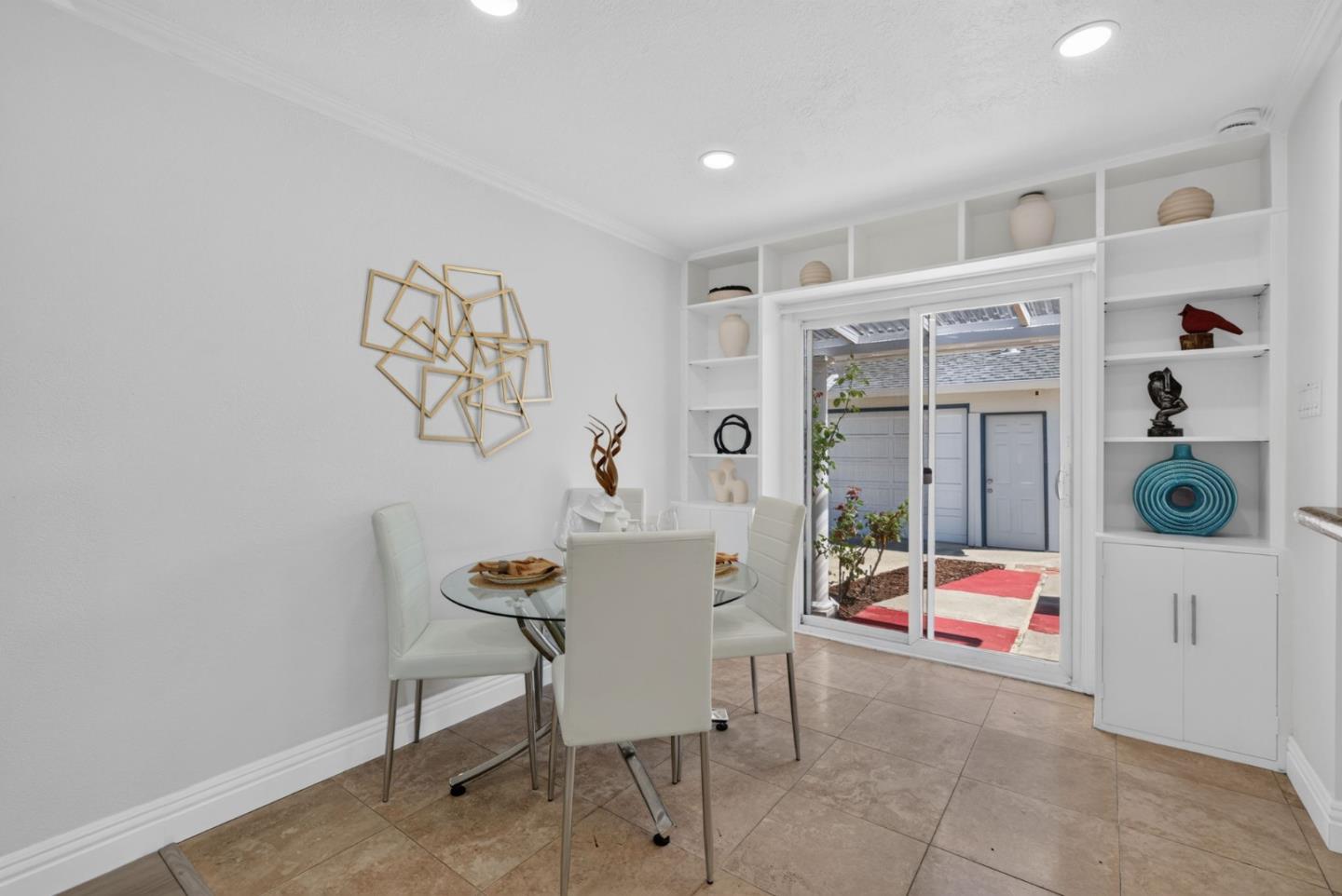 Dining area with built-in shelving, a glass-top table, and sliding glass doors to the patio.