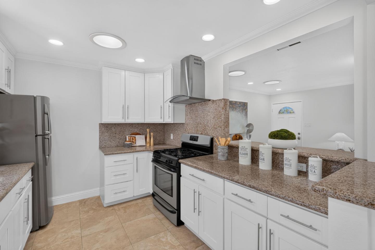 Kitchen with white cabinetry, speckled stone counters, and stainless steel appliances.
