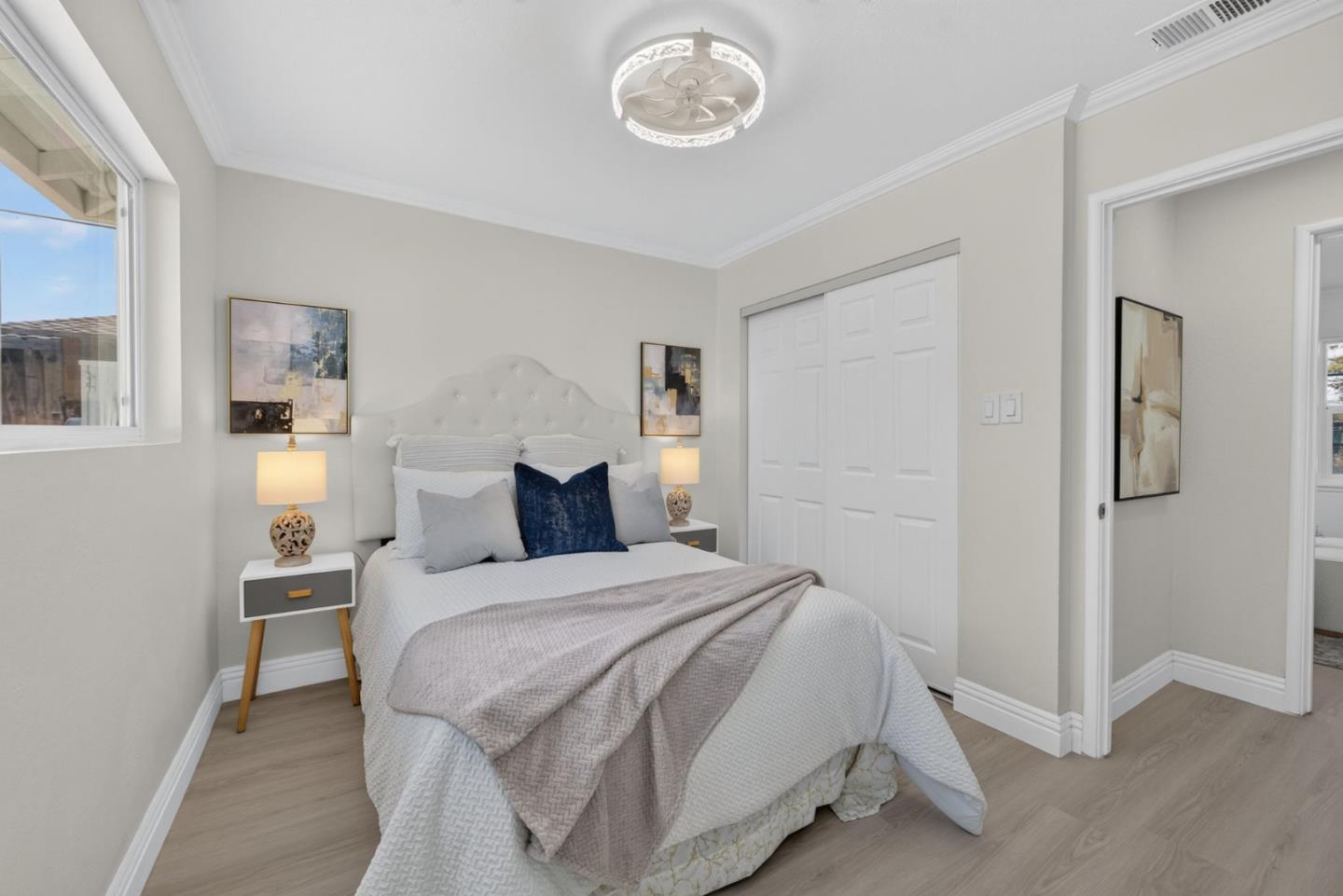 Bright staged bedroom with a white bed, tufted headboard, navy accent pillow, and sliding closet doors.
