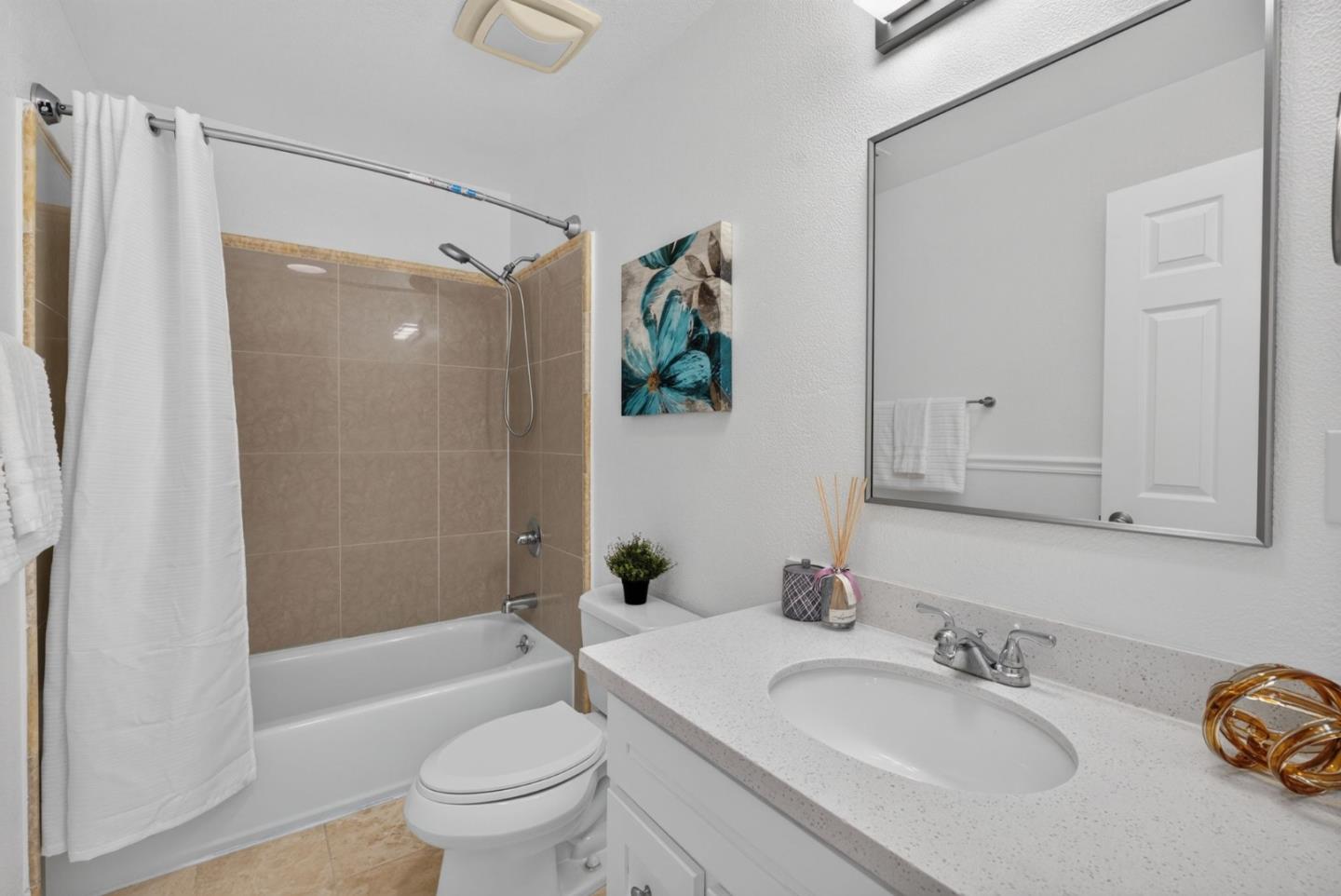 Bathroom with a tiled tub and shower, white vanity, and large mirror.