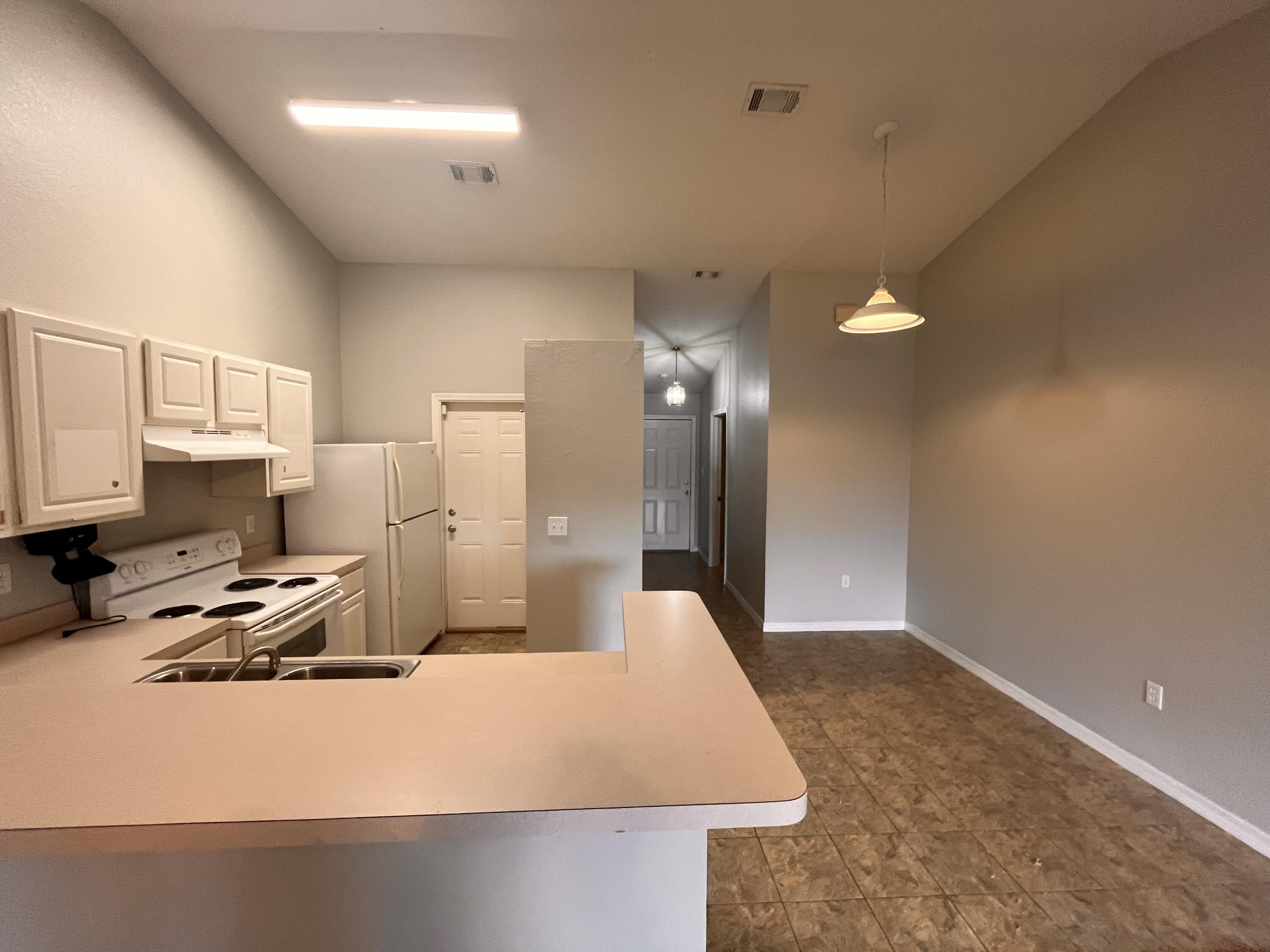 Kitchen with white cabinets and appliances, a breakfast bar, and adjoining open dining area.