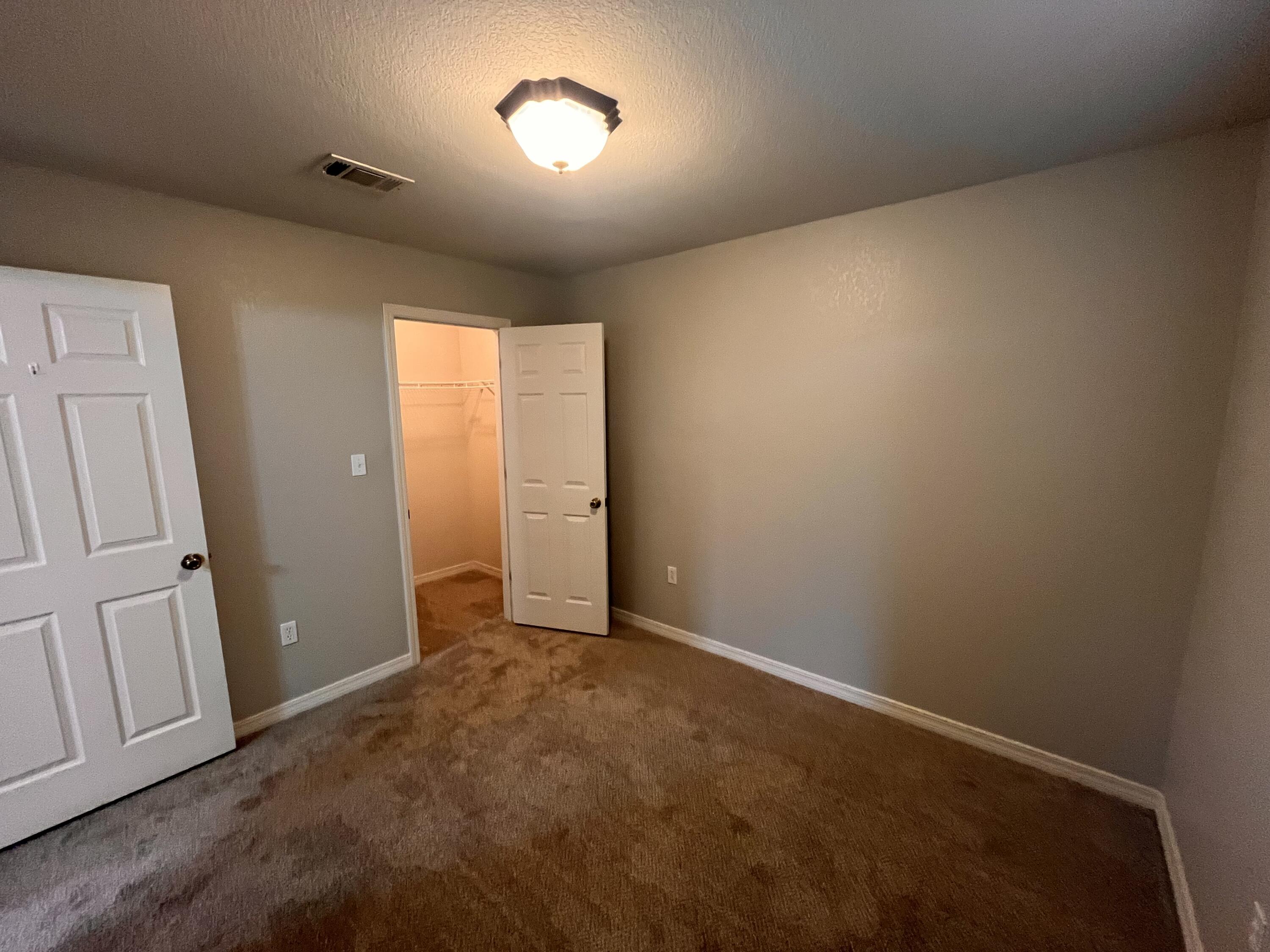 Empty bedroom with brown carpet and an open closet door.