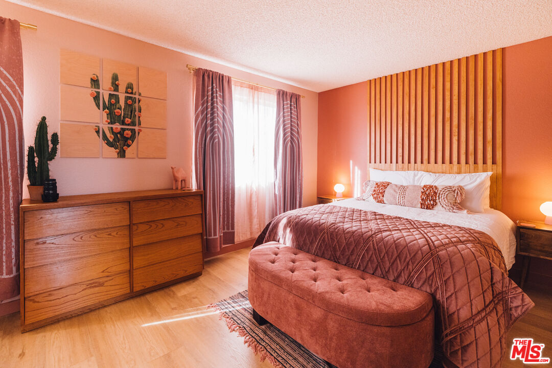 Furnished bedroom with a wood-slat headboard, rust-colored bedding, and cactus decor.