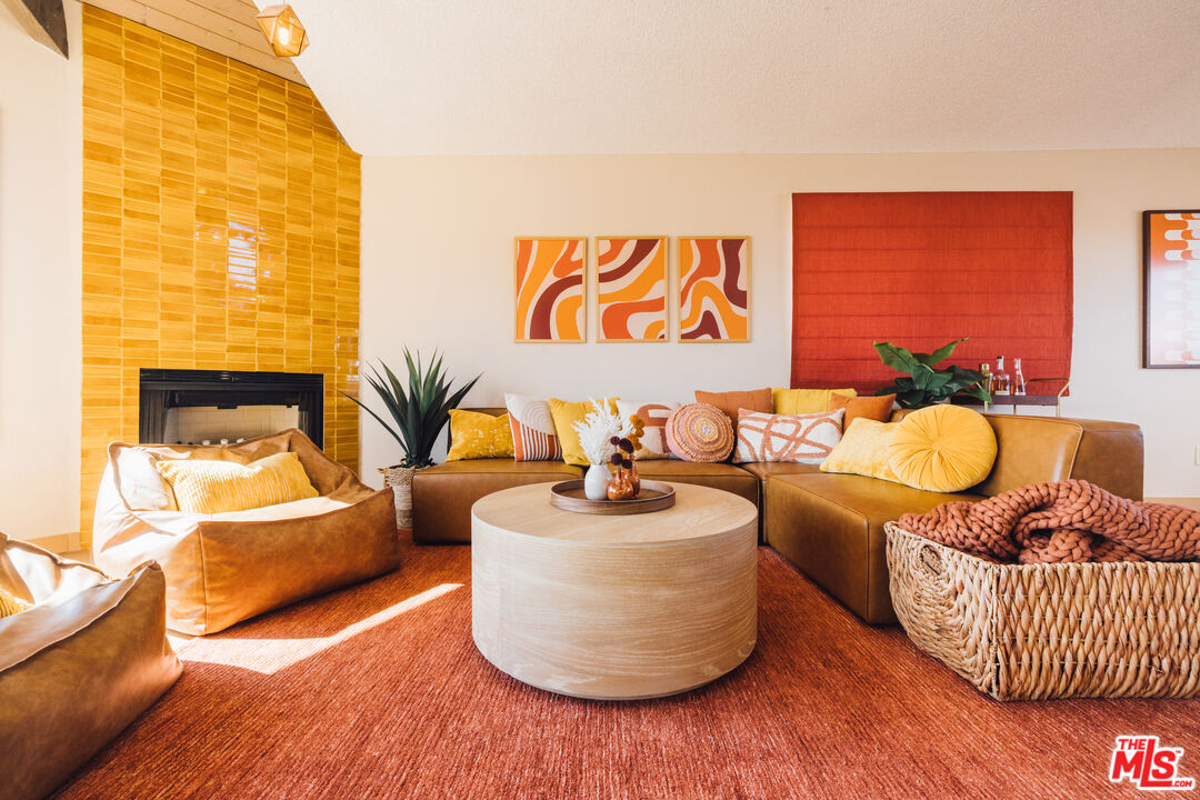 Living room with caramel leather seating, a mustard tile fireplace wall, and colorful abstract art.