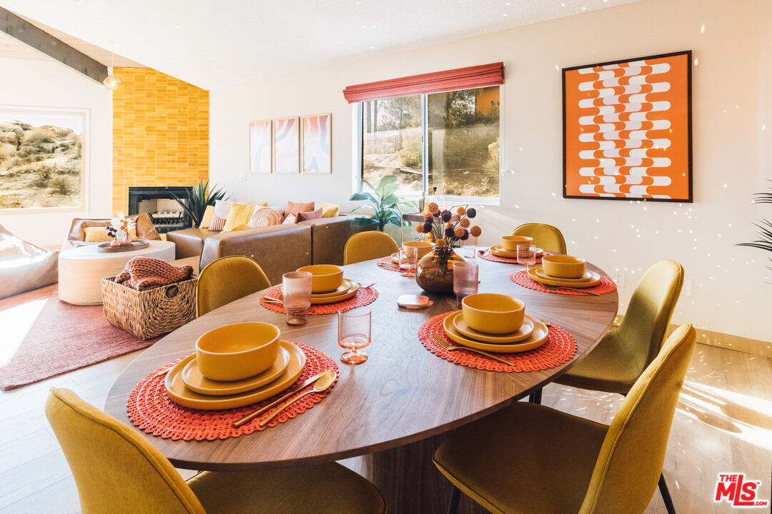 Dining room with a set oval table, mustard-yellow chairs, and an orange tile fireplace wall.
