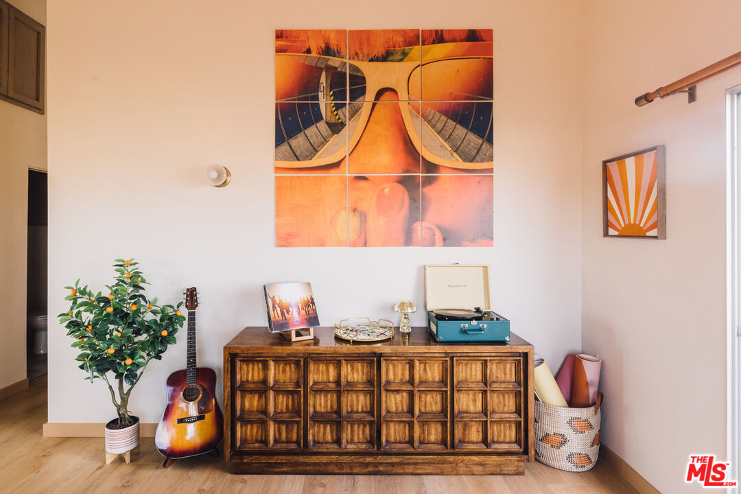 Furnished interior with a carved wooden sideboard, turquoise record player, guitar, and colorful wall art.