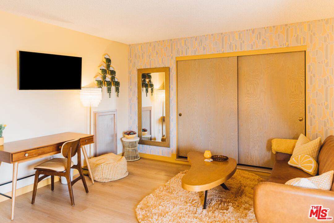 Furnished living room with a brown sofa, sculptural coffee table, desk, and large sliding wood doors.