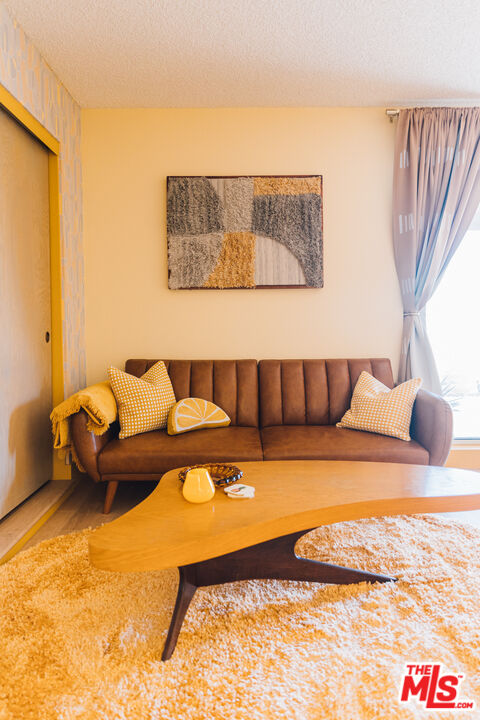 Living room with a brown sofa, yellow accents, and a sculptural wood coffee table.