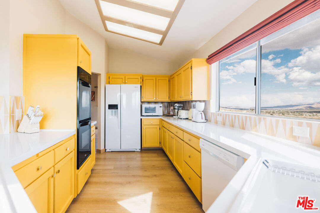 Kitchen with bright yellow cabinets, skylights, and a large window overlooking the desert.