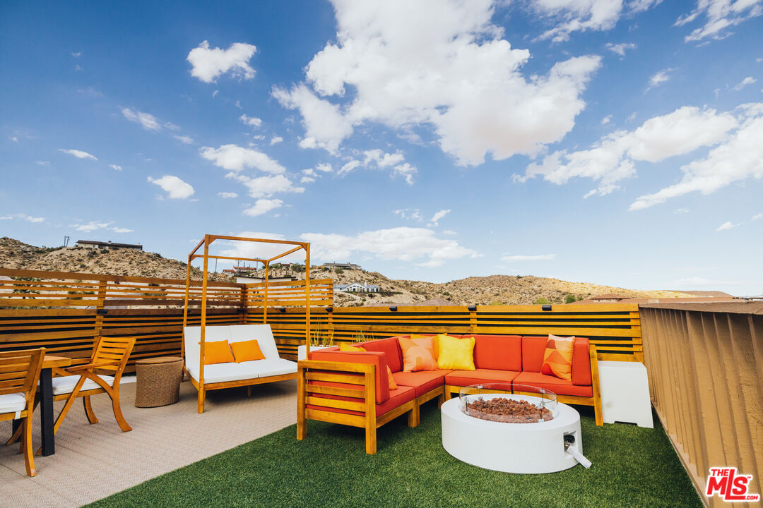 Rooftop deck with colorful lounge seating and fire pit overlooking rocky desert hills.