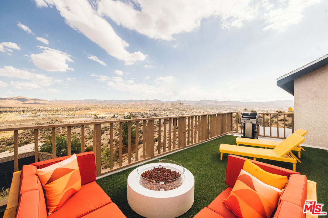 Rooftop deck with orange lounge seating and a fire pit overlooking a desert valley.