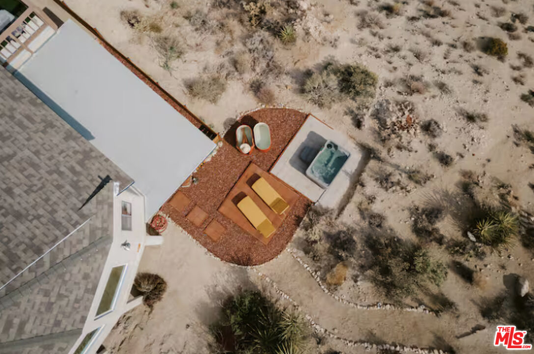 Aerial view of a desert home’s patio with lounge chairs and a hot tub.