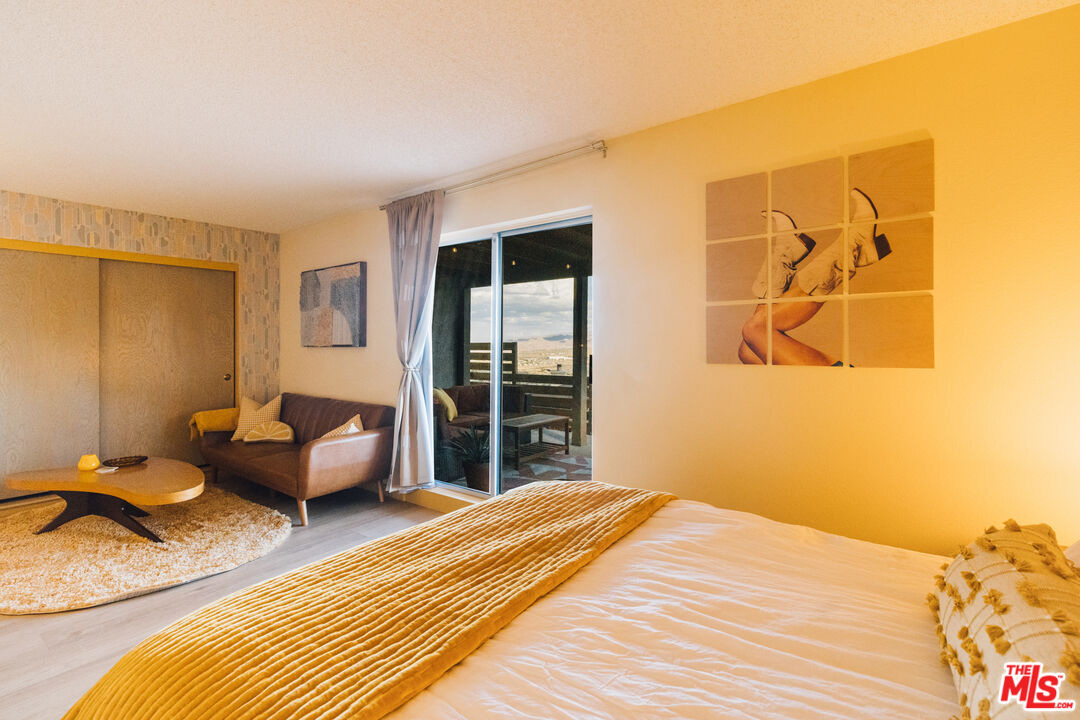 Furnished bedroom with a mustard-yellow coverlet, sitting area, and sliding doors to a desert-view patio.