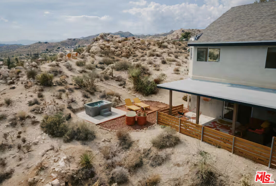 Desert home with a covered patio, hot tub, and rocky mountain landscape.