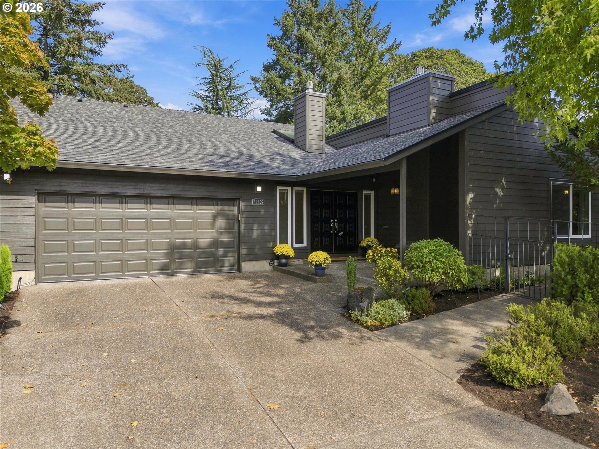 Dark gray home with a double garage, covered entry, and landscaped front garden.