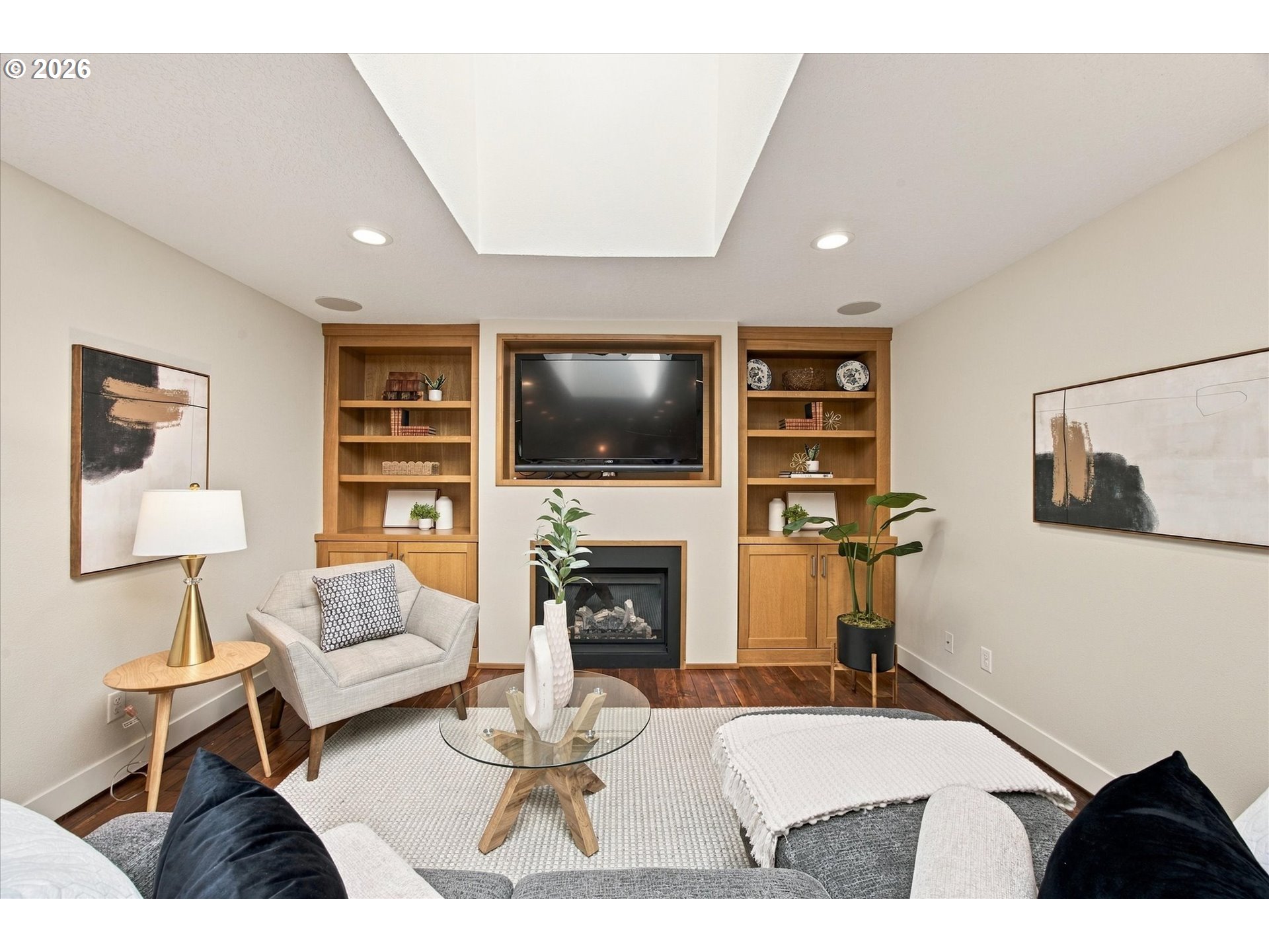 Living room with built-in wooden shelving, a television, and a gas fireplace.