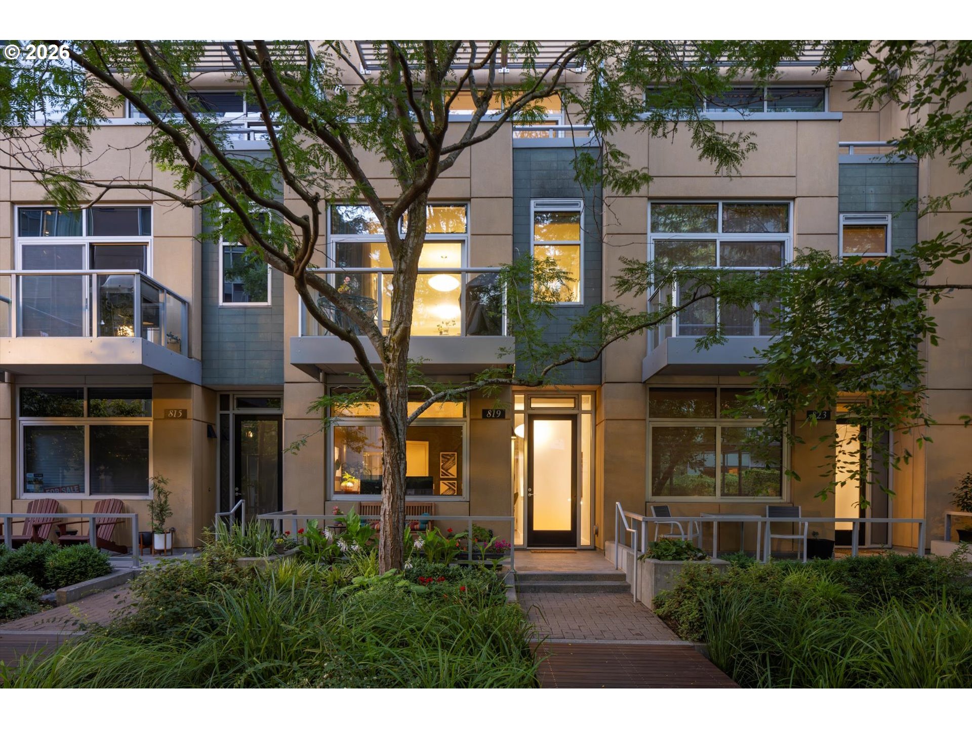 Modern residence at 819 with a warmly lit entrance, private patio, and landscaped courtyard.