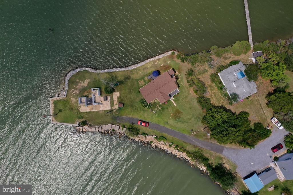 Aerial view of a waterfront property with a curved shoreline, several buildings, and a dock.