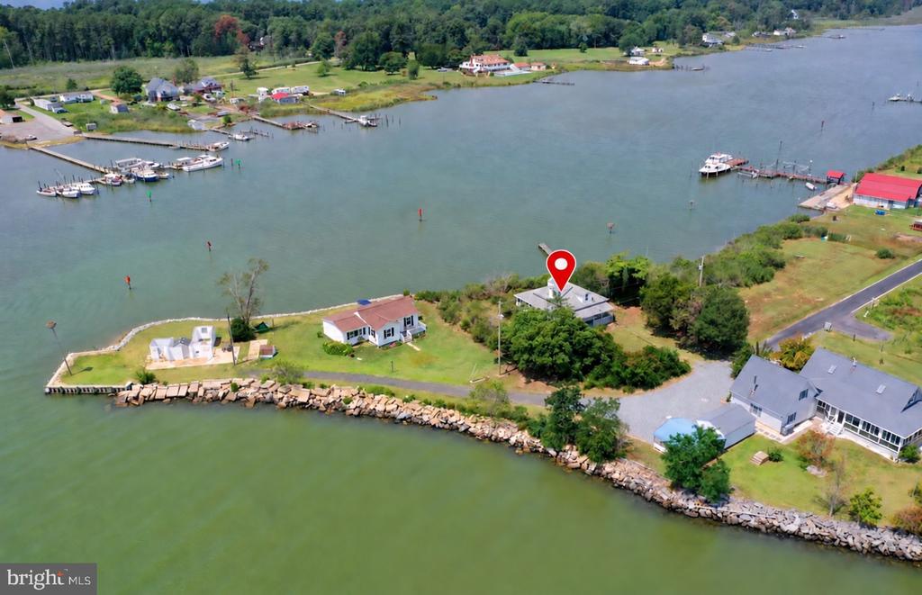 Aerial waterfront homes beside a broad inlet, with docks and a red pin marking one property.