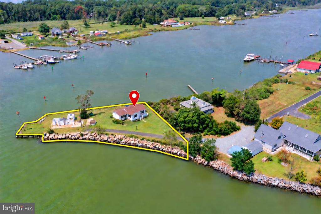 Waterfront property with a house and rocky shoreline, outlined in yellow beside an inlet.