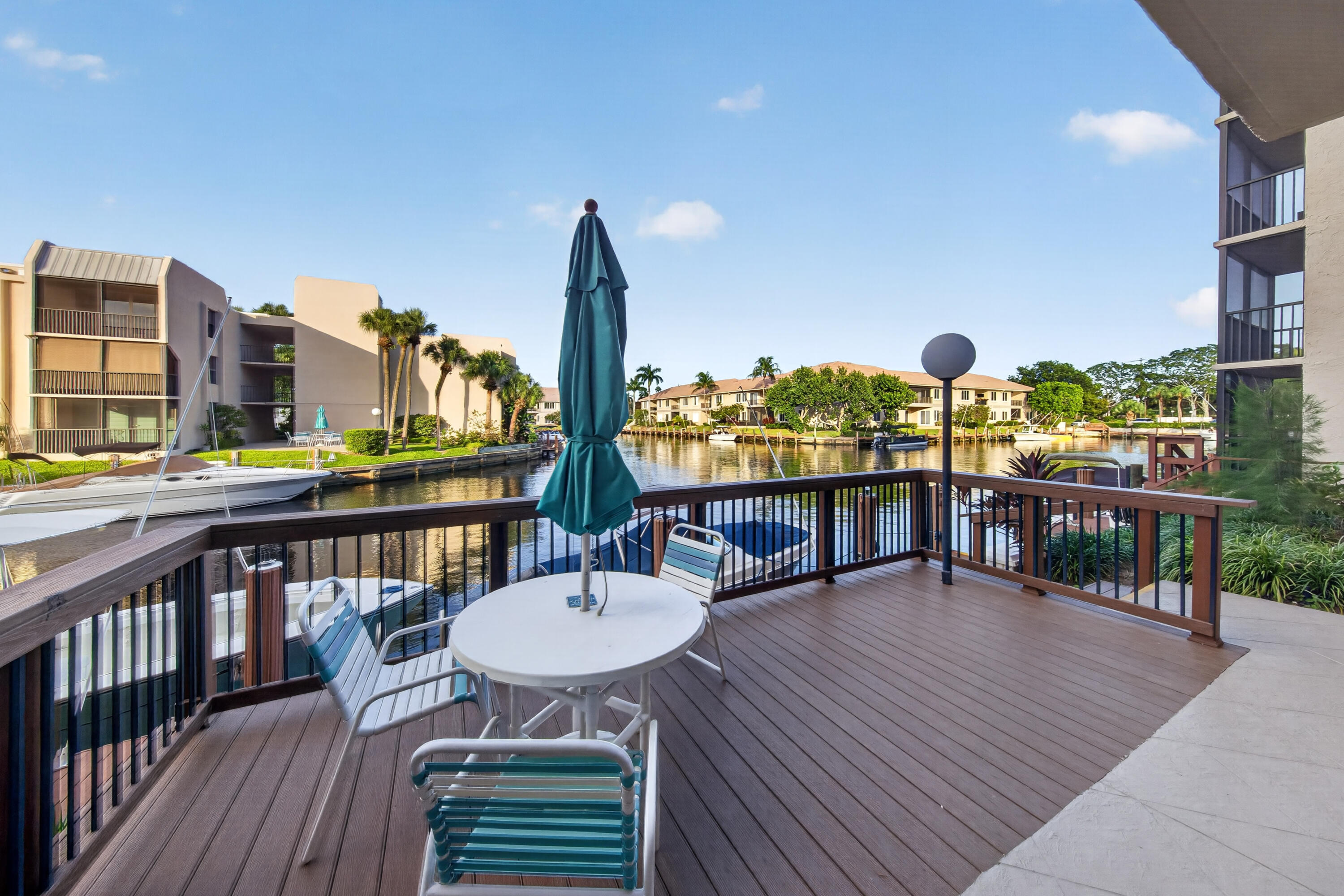 Waterfront balcony with patio seating overlooking a canal and boats.