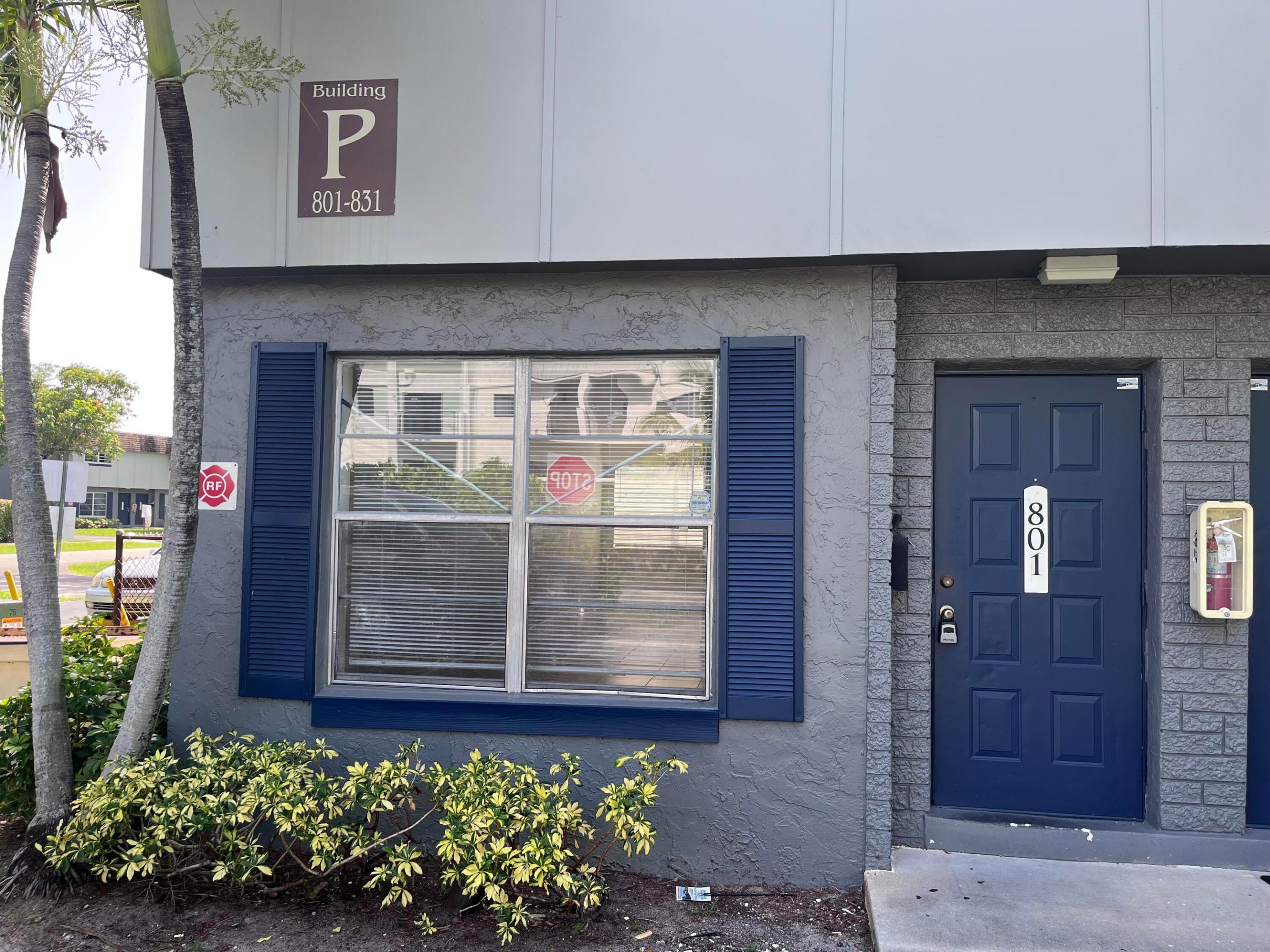 Unit 801 entrance with a navy blue door, matching window shutters, and shrubs.