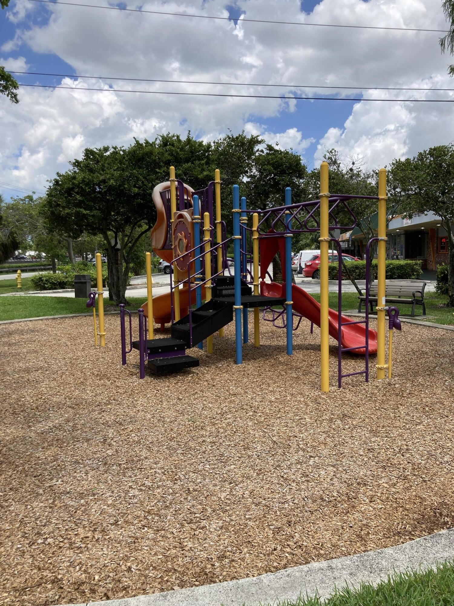 Outdoor playground with colorful slides and climbing equipment on a wood-chip surface.