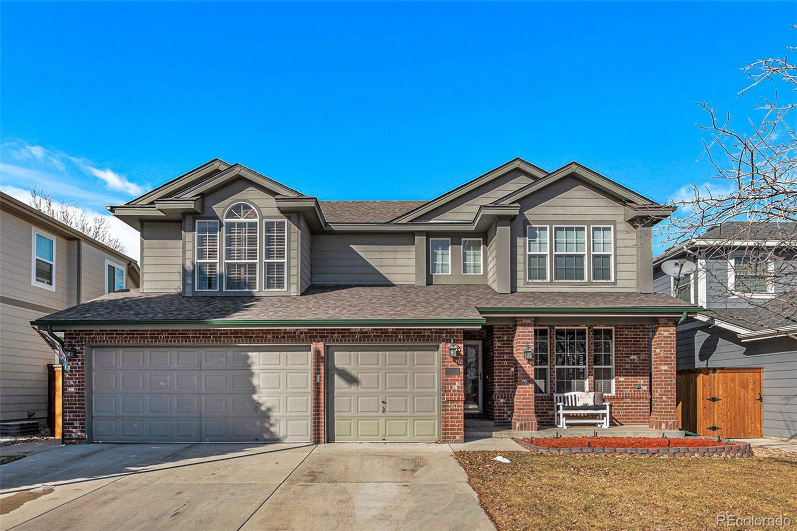 Two-story brick and gray-sided home with a two-car garage and broad driveway.