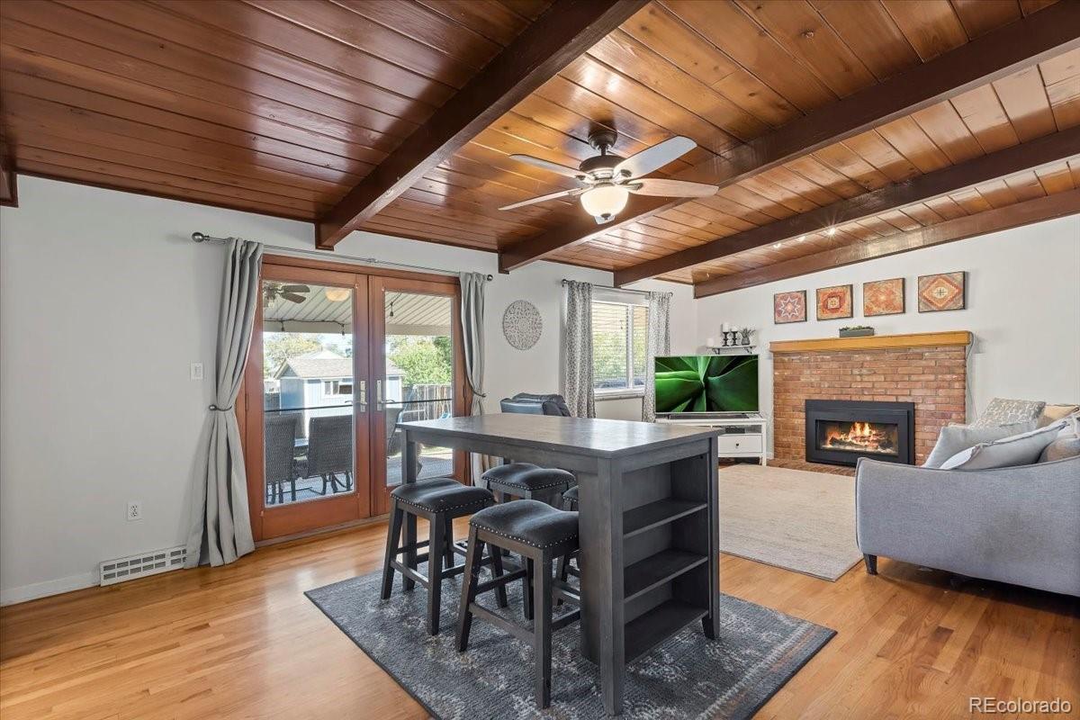 Living room with exposed wood beams, brick fireplace, and French doors to a patio