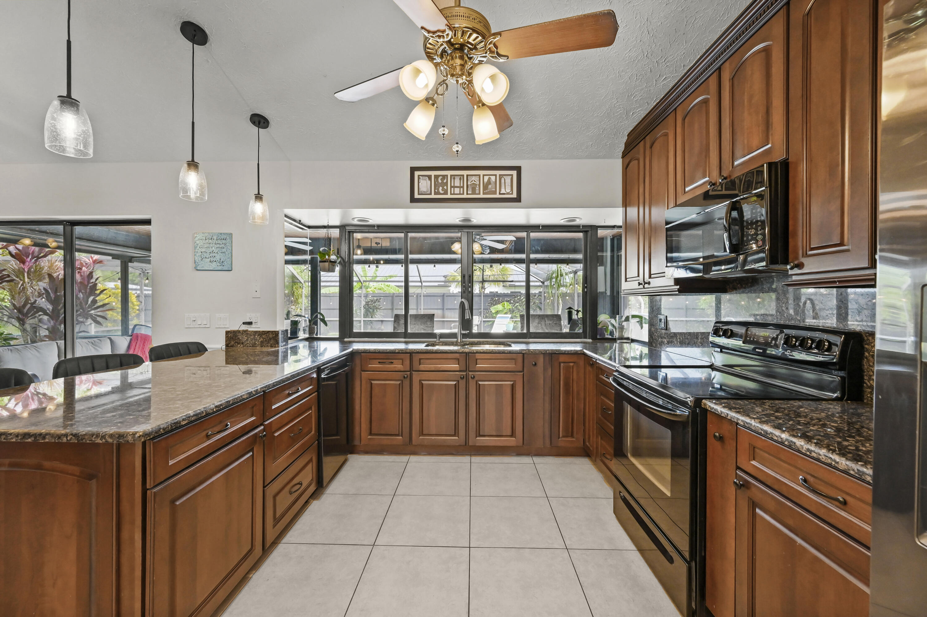 Kitchen with rich wood cabinets, granite counters, and a wide window over the sink.